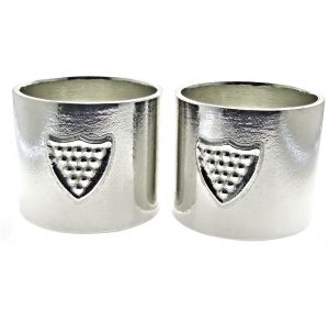 Pair of Cornish tin napkin rings with shield motif.